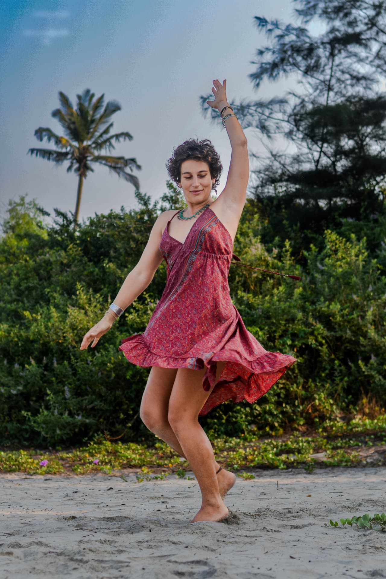 Woman dancing barefoot on a tropical beach at dusk